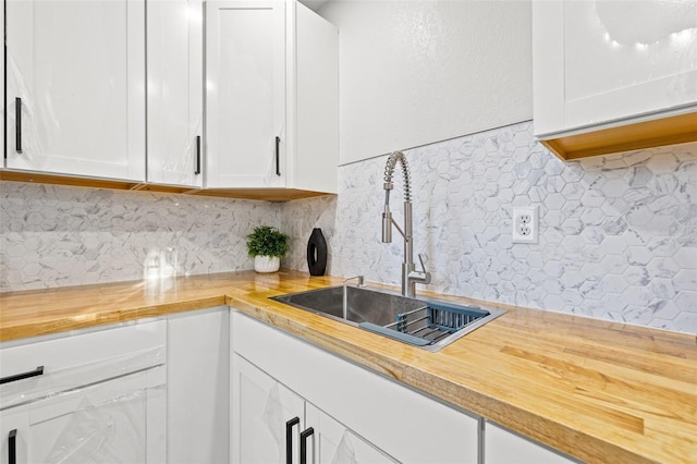 kitchen with sink, backsplash, white cabinets, and wood counters