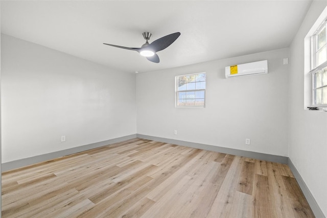 empty room featuring a wall mounted air conditioner, ceiling fan, and light wood-type flooring