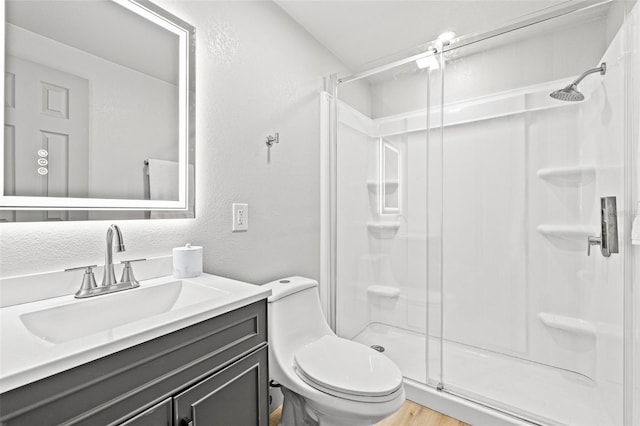 bathroom featuring walk in shower, wood-type flooring, vanity, and toilet