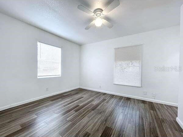 empty room with dark wood-type flooring and ceiling fan