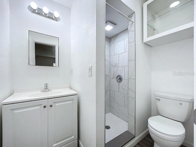 bathroom featuring vanity, toilet, and a tile shower