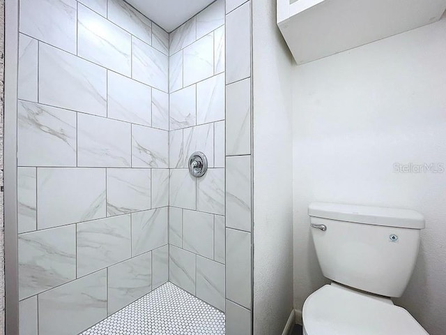 bathroom with a tile shower and toilet