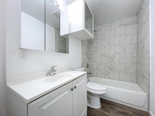 full bathroom featuring vanity, tiled shower / bath combo, wood-type flooring, and toilet