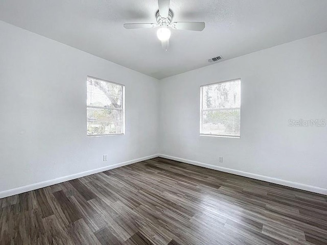 unfurnished room featuring dark wood-type flooring, a wealth of natural light, and ceiling fan