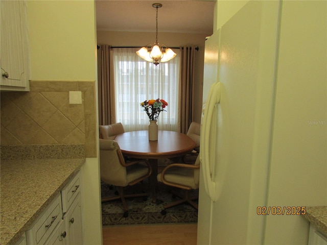 dining space with an inviting chandelier and light hardwood / wood-style flooring