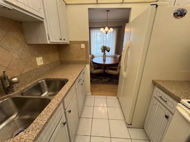 kitchen featuring a chandelier, decorative backsplash, a sink, light tile patterned flooring, and freestanding refrigerator