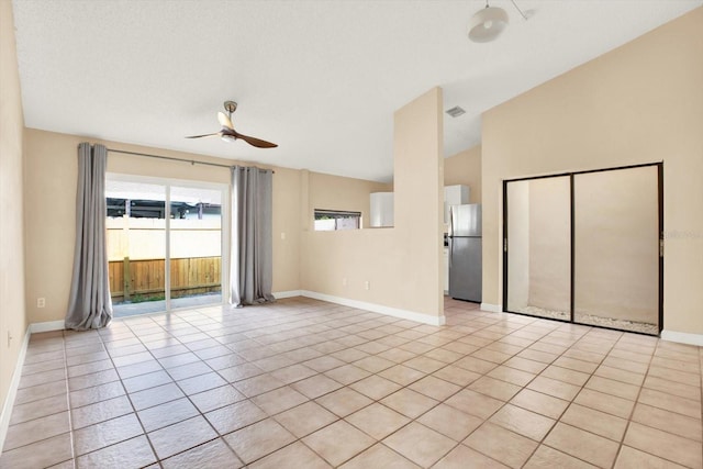 empty room with lofted ceiling, light tile patterned floors, a textured ceiling, and ceiling fan