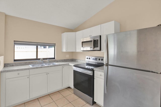 kitchen with vaulted ceiling, light tile patterned flooring, sink, white cabinets, and stainless steel appliances