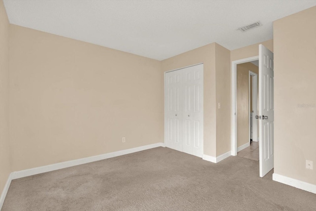 unfurnished bedroom with light carpet and a closet