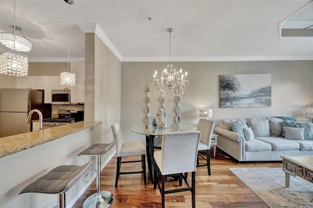 dining area with crown molding, light wood-type flooring, and a notable chandelier