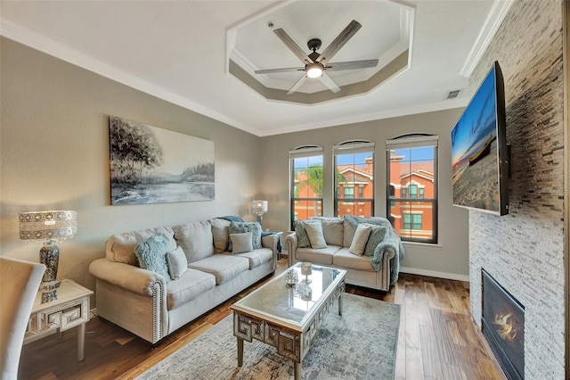 living room featuring crown molding, dark hardwood / wood-style floors, a raised ceiling, and ceiling fan