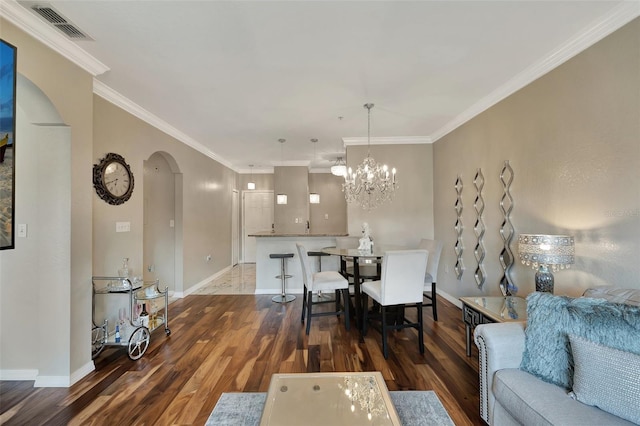 dining area featuring an inviting chandelier, ornamental molding, and dark hardwood / wood-style flooring