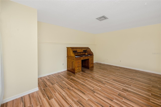 unfurnished room with light hardwood / wood-style flooring and a textured ceiling