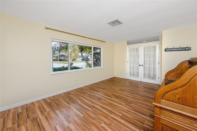 unfurnished room with wood-type flooring, french doors, and a textured ceiling