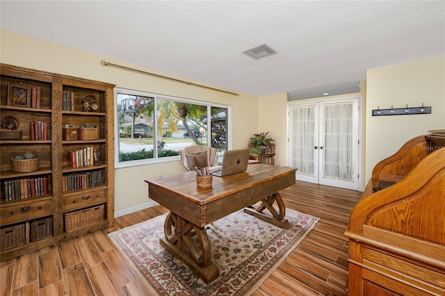 office featuring french doors, a textured ceiling, and light wood-type flooring