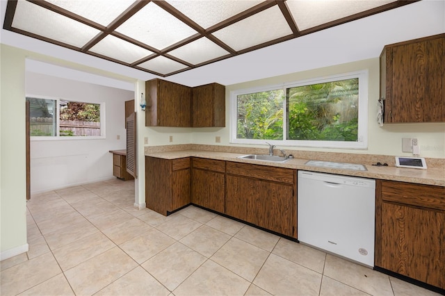 kitchen featuring white dishwasher, sink, light tile patterned floors, and a healthy amount of sunlight