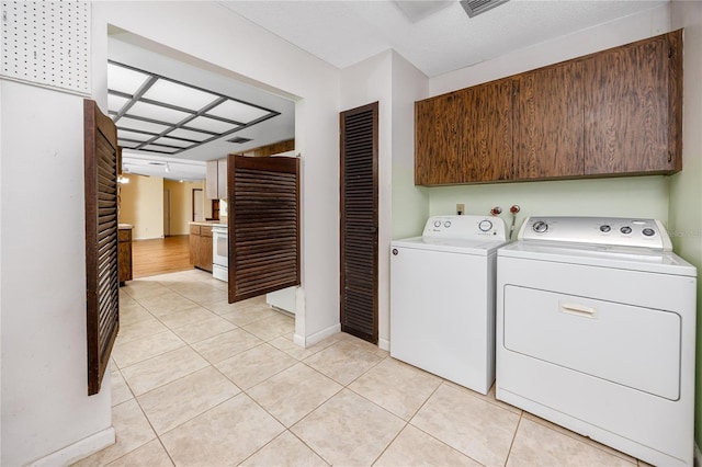 laundry room with cabinets, light tile patterned flooring, and independent washer and dryer