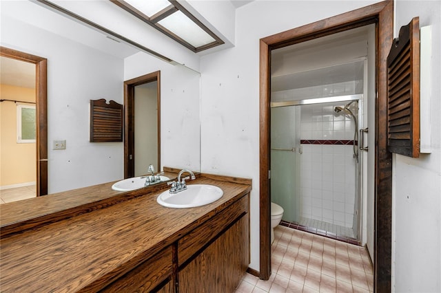 bathroom featuring a shower with door, vanity, tile patterned flooring, and toilet