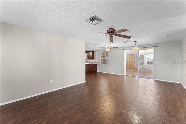 unfurnished living room featuring ceiling fan, dark hardwood / wood-style flooring, and a textured ceiling