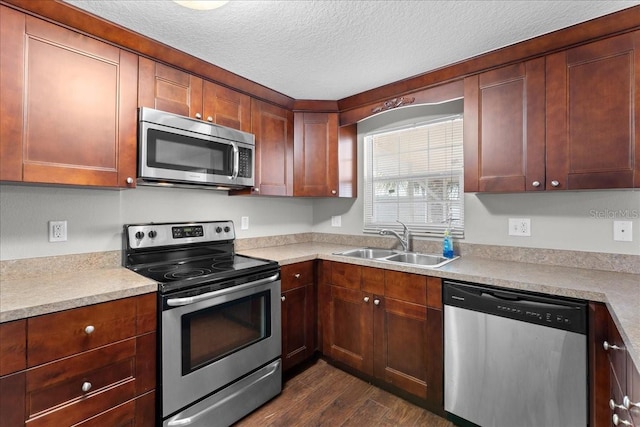 kitchen featuring appliances with stainless steel finishes, sink, a textured ceiling, and dark hardwood / wood-style floors