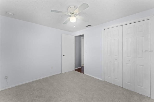 unfurnished bedroom with ceiling fan, carpet flooring, a closet, and a textured ceiling