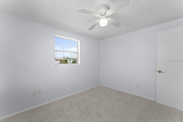 empty room with ceiling fan, light colored carpet, and a textured ceiling