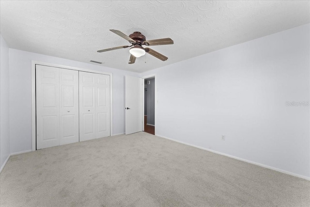 unfurnished bedroom featuring ceiling fan, carpet flooring, a textured ceiling, and a closet