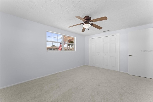 unfurnished bedroom featuring ceiling fan, carpet floors, a closet, and a textured ceiling