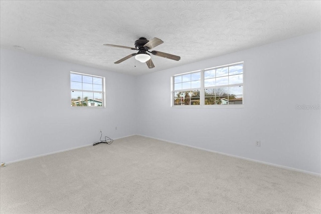 carpeted empty room featuring ceiling fan, a healthy amount of sunlight, and a textured ceiling