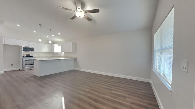 kitchen featuring white cabinetry, decorative light fixtures, appliances with stainless steel finishes, kitchen peninsula, and hardwood / wood-style floors