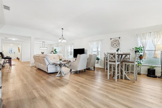 living room featuring light hardwood / wood-style flooring, a chandelier, and vaulted ceiling