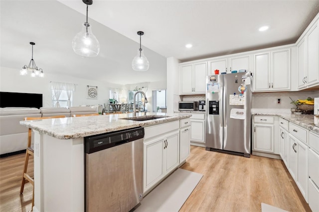 kitchen with white cabinetry, appliances with stainless steel finishes, sink, and a center island with sink