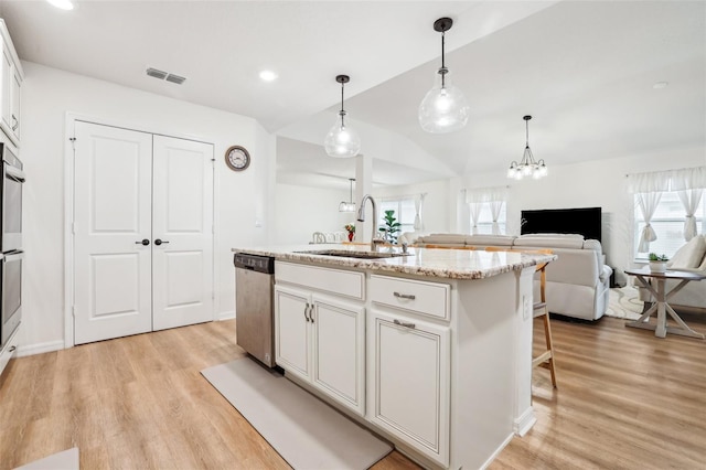 kitchen featuring sink, dishwasher, an island with sink, white cabinets, and decorative light fixtures