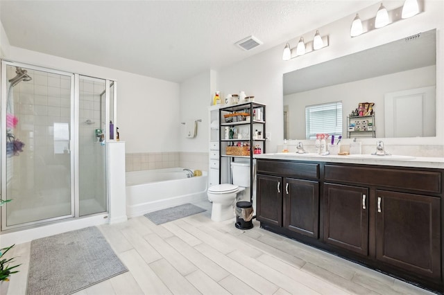 full bathroom with hardwood / wood-style floors, separate shower and tub, vanity, a textured ceiling, and toilet