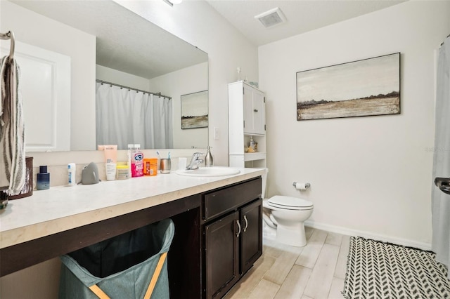 bathroom with vanity, toilet, and hardwood / wood-style floors