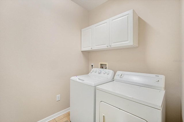 laundry area with cabinets, light tile patterned floors, and washing machine and clothes dryer