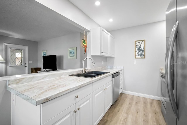 kitchen featuring white cabinetry, sink, kitchen peninsula, stainless steel appliances, and light hardwood / wood-style flooring