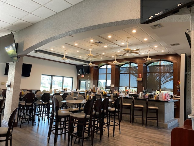 dining area with ceiling fan, indoor bar, and hardwood / wood-style floors