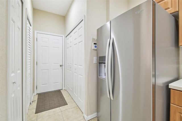 kitchen with light tile patterned floors and stainless steel fridge