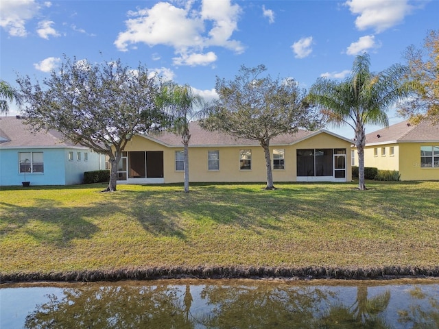 rear view of property featuring a sunroom and a lawn