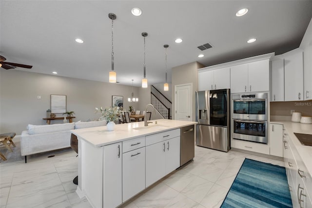 kitchen featuring marble finish floor, stainless steel appliances, open floor plan, white cabinetry, and a sink