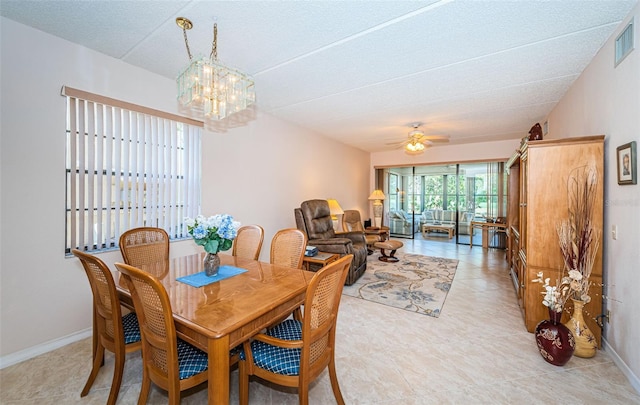 dining space with ceiling fan with notable chandelier