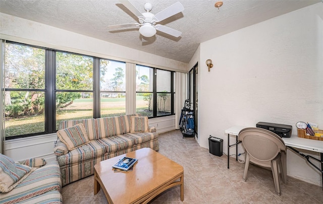 living room featuring ceiling fan and a textured ceiling