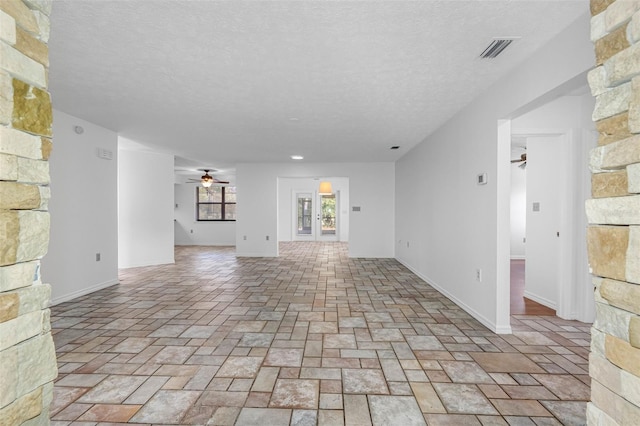 unfurnished living room with ceiling fan and a textured ceiling