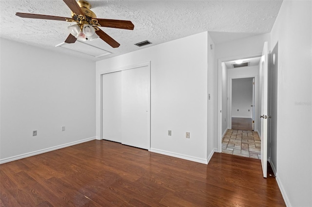 unfurnished bedroom featuring dark wood-type flooring, a closet, and a textured ceiling