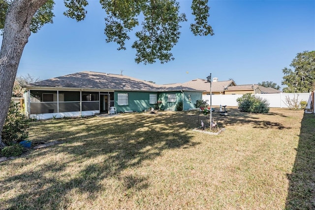 rear view of property featuring a yard and a sunroom