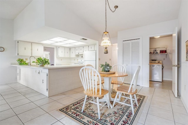 dining area with lofted ceiling, washer / dryer, sink, and light tile patterned floors