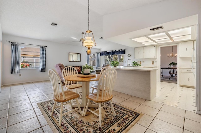 dining area featuring sink, light tile patterned floors, a textured ceiling, and a chandelier