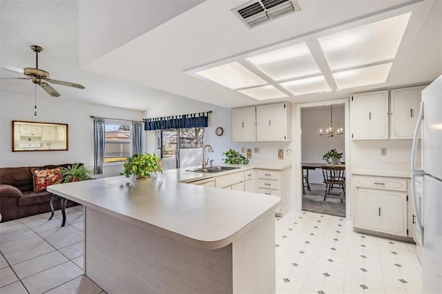 kitchen featuring white refrigerator, ceiling fan with notable chandelier, kitchen peninsula, and sink