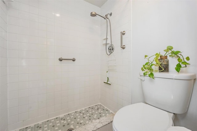 bathroom featuring a tile shower and toilet